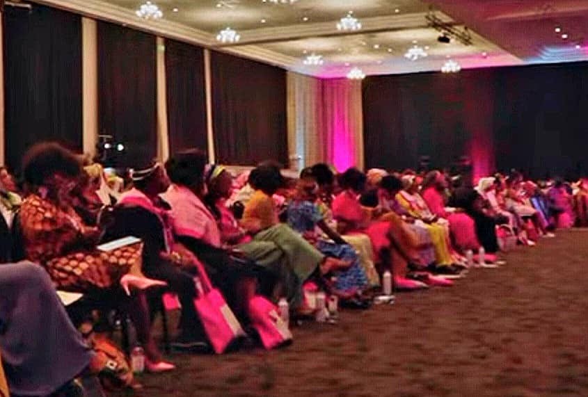 photo taken during African Women in Dialogue (AfWID) conference, A wide shot of a conference hall filled with women sitting in rows, facing a stage